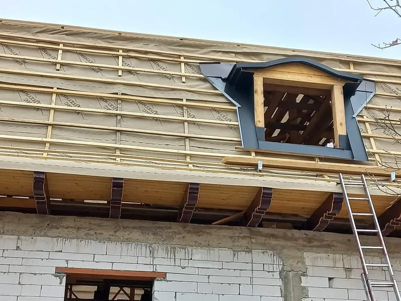 Montator cu echipament de siguranță instalând țiglă metalică